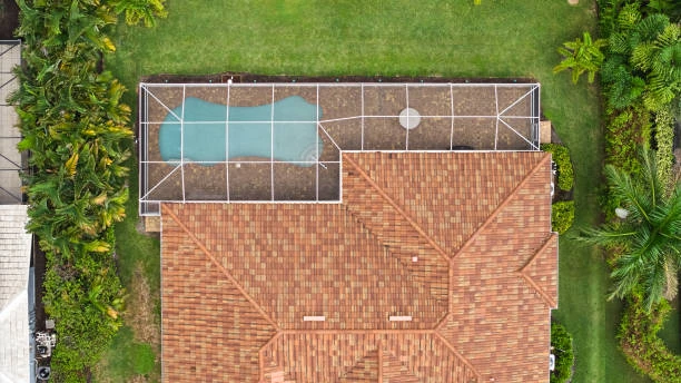 Overhead view of a tile-roof home with a screened pool